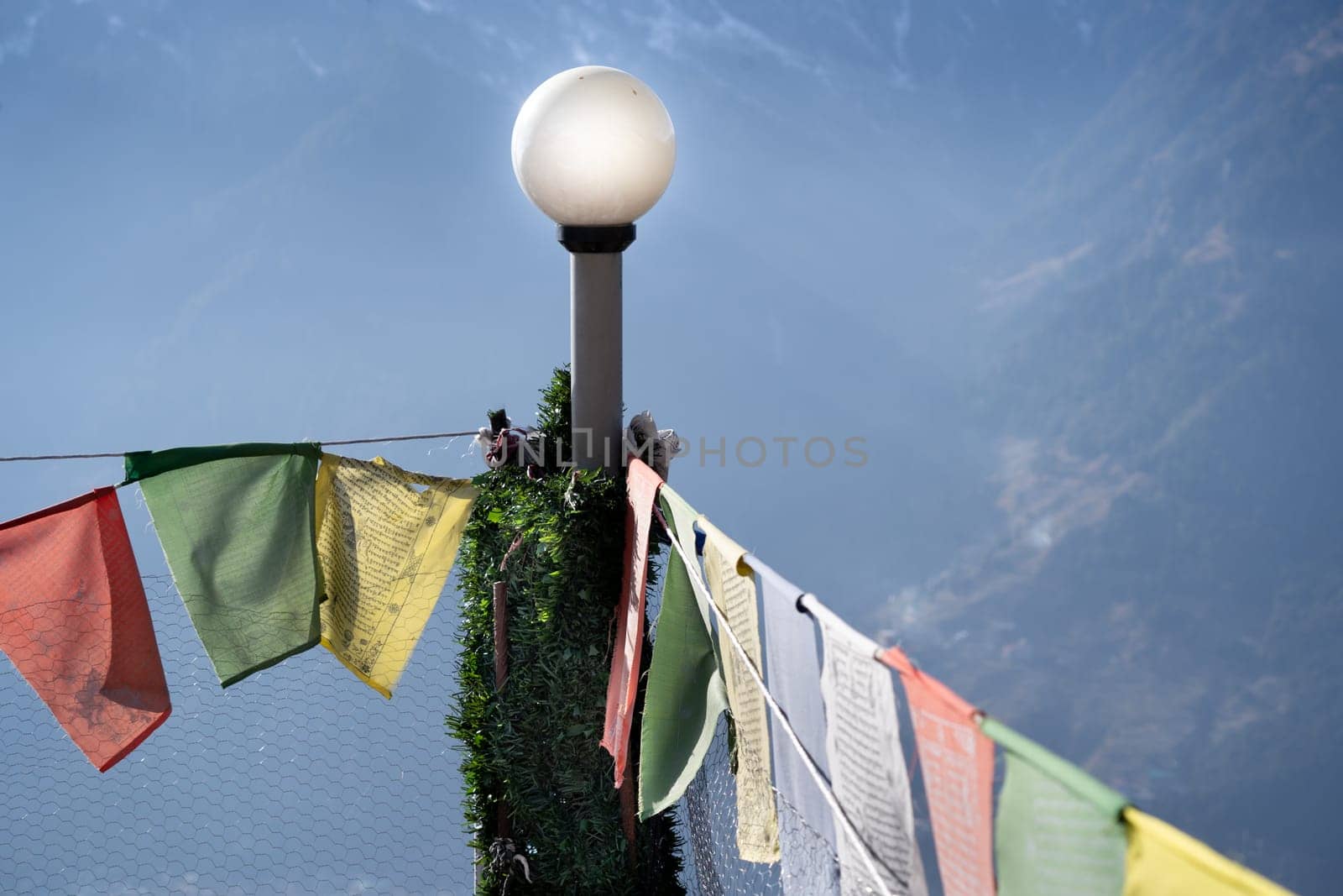 sacred religious multicolored prayer flags on fence moving in the wind showing a bhuddist prayer incantation common in hill stations in Himachal Pradesh India