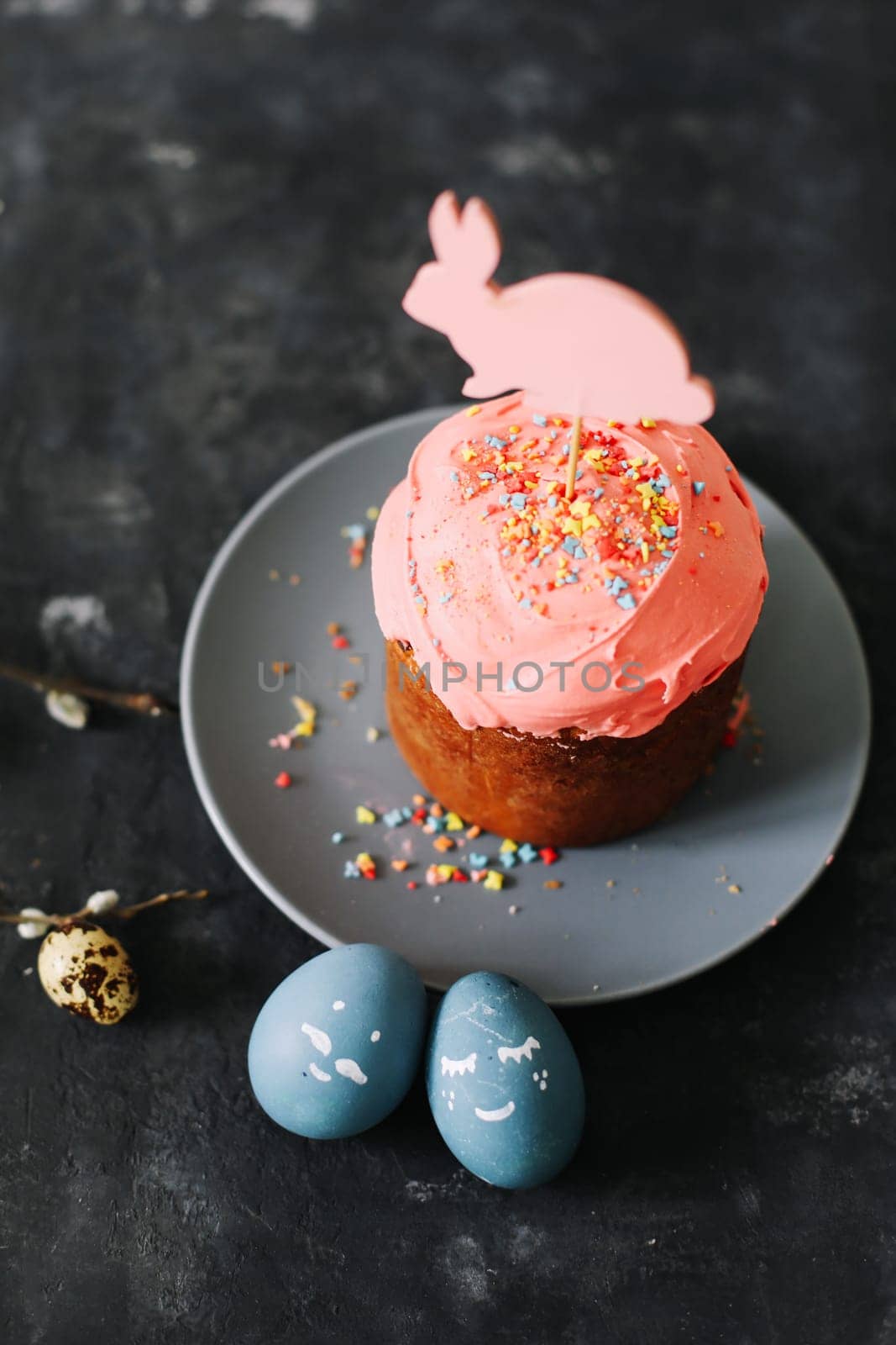 Plate with tasty Easter cake, eggs and willow branches on dark background. High quality photo