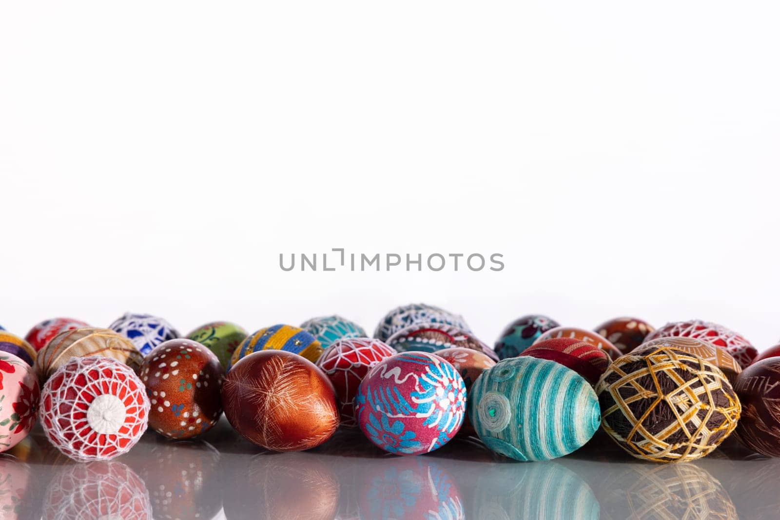 Composition of Easter eggs set in a row on a solid white background. The set Easter decoration is reflected in the glass.