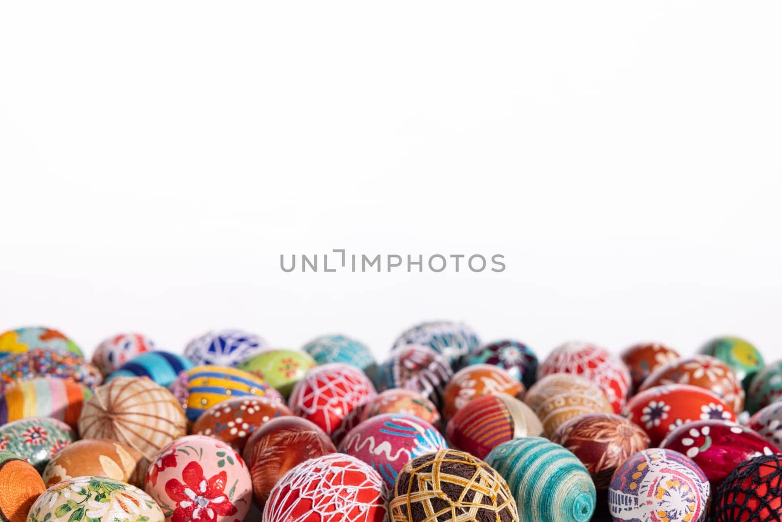 Easter eggs made in different technologies and arranged on a white background in rather random places. A large number of colorful eggs lying side by side.