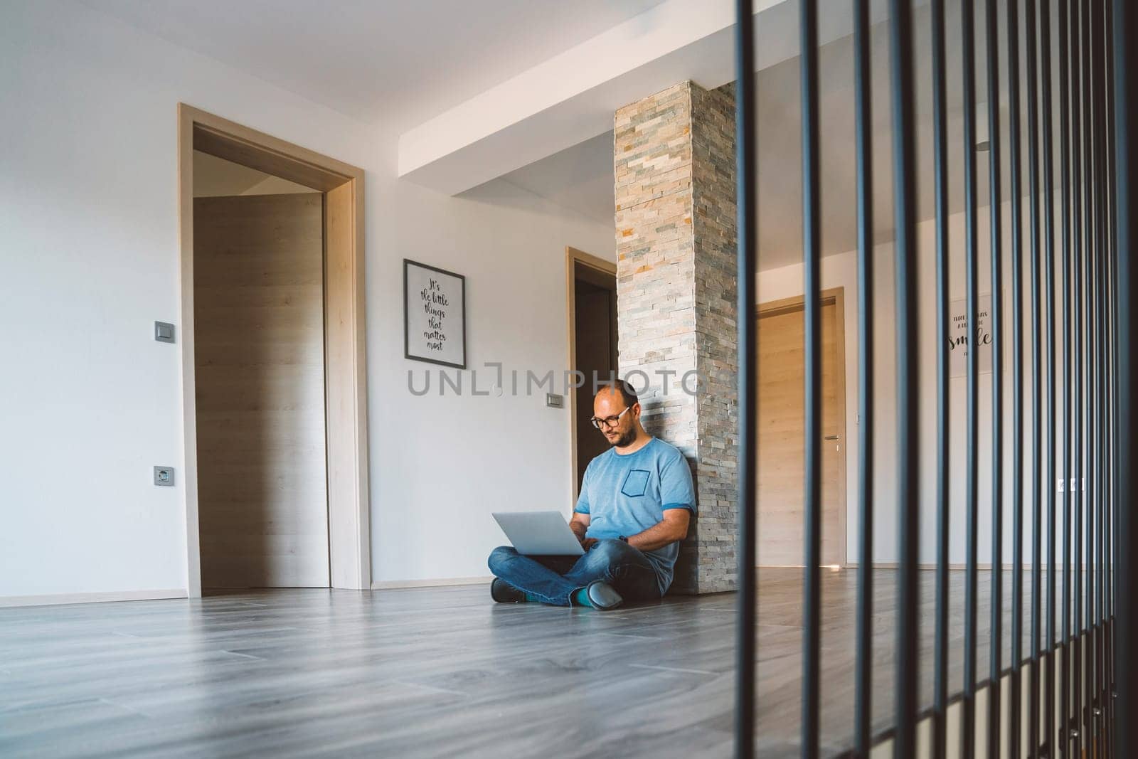 Man working from home on the laptop sitting on the floor on the hallway by VisualProductions