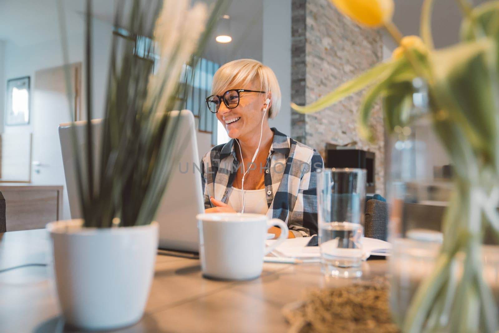 Adult caucasian woman working from home a couple days a week. Adult person working from home, from different rooms in the house, in the kitchen, dining room, office.