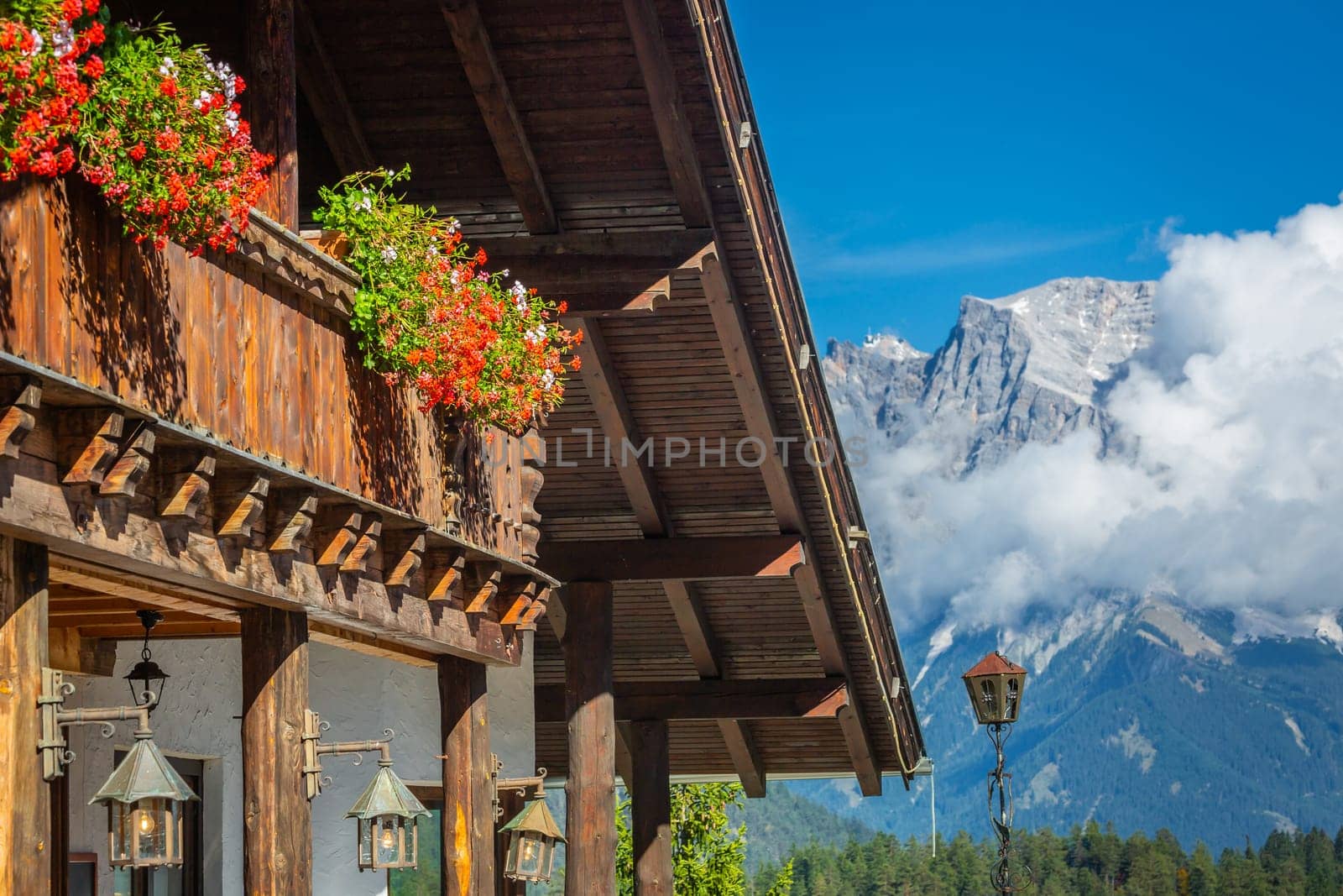 Alpine Chalet with flowers at springtime, facing Zugspitze mountain, Bavarian Alps, Germany