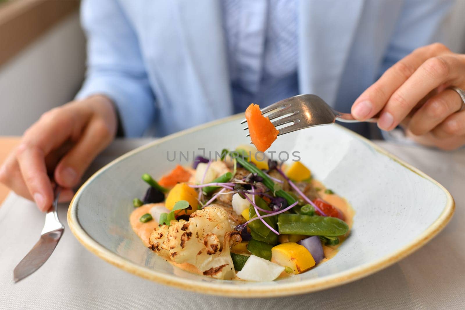 Woman eating fish with vegetables in a restaurant