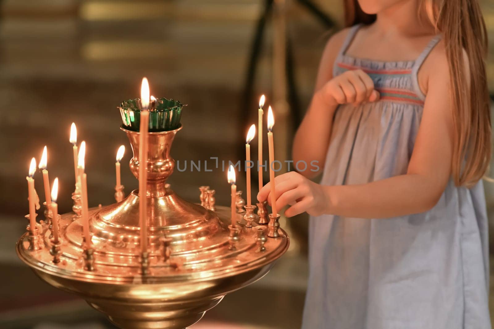 little girl puts a candle in church. Orthodoxy and children