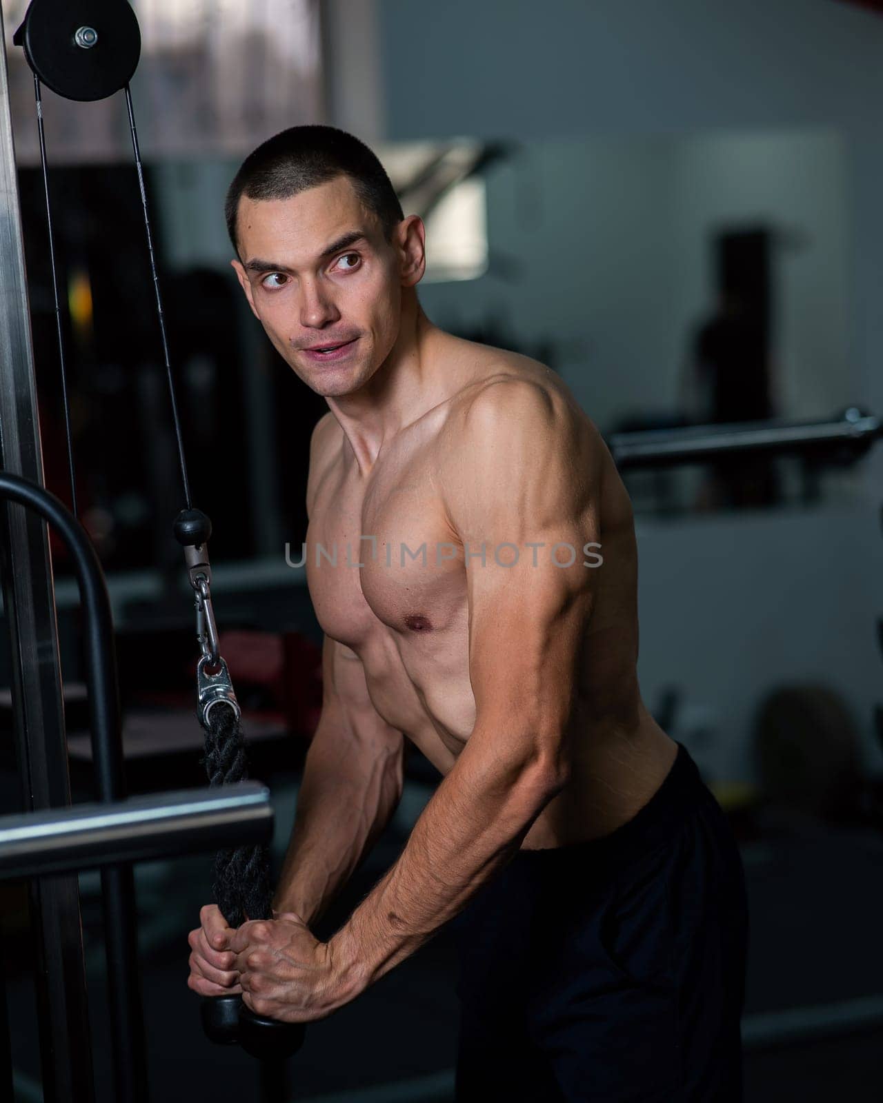 Shirtless man doing triceps pulldown at the gym. by mrwed54