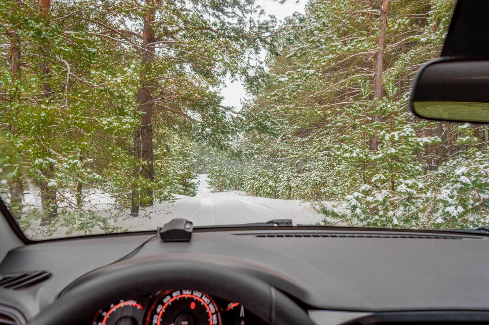 a car on a snowy road in a winter forest by roman112007