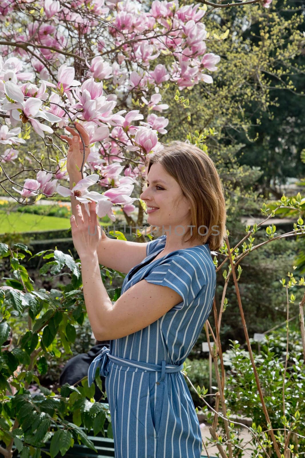 blonde with pleasure inhales an aroman of magnolia flowers standing under a tree. High quality photo