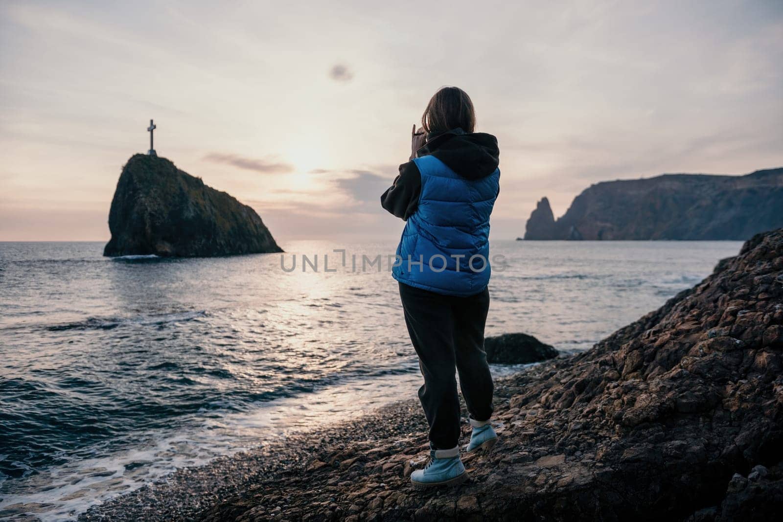 Woman travel sea. Happy tourist taking picture outdoors for memories. Woman traveler looks at the edge of the cliff on the sea bay of mountains, sharing travel adventure journey.