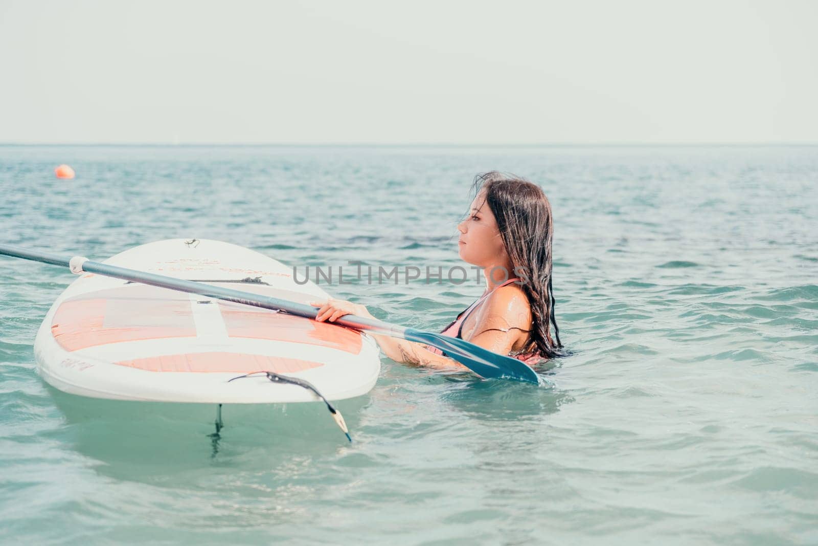 Sea woman sup. Silhouette of happy young woman in pink bikini, surfing on SUP board, confident paddling through water surface. Idyllic sunset. Active lifestyle at sea or river. Slow motion