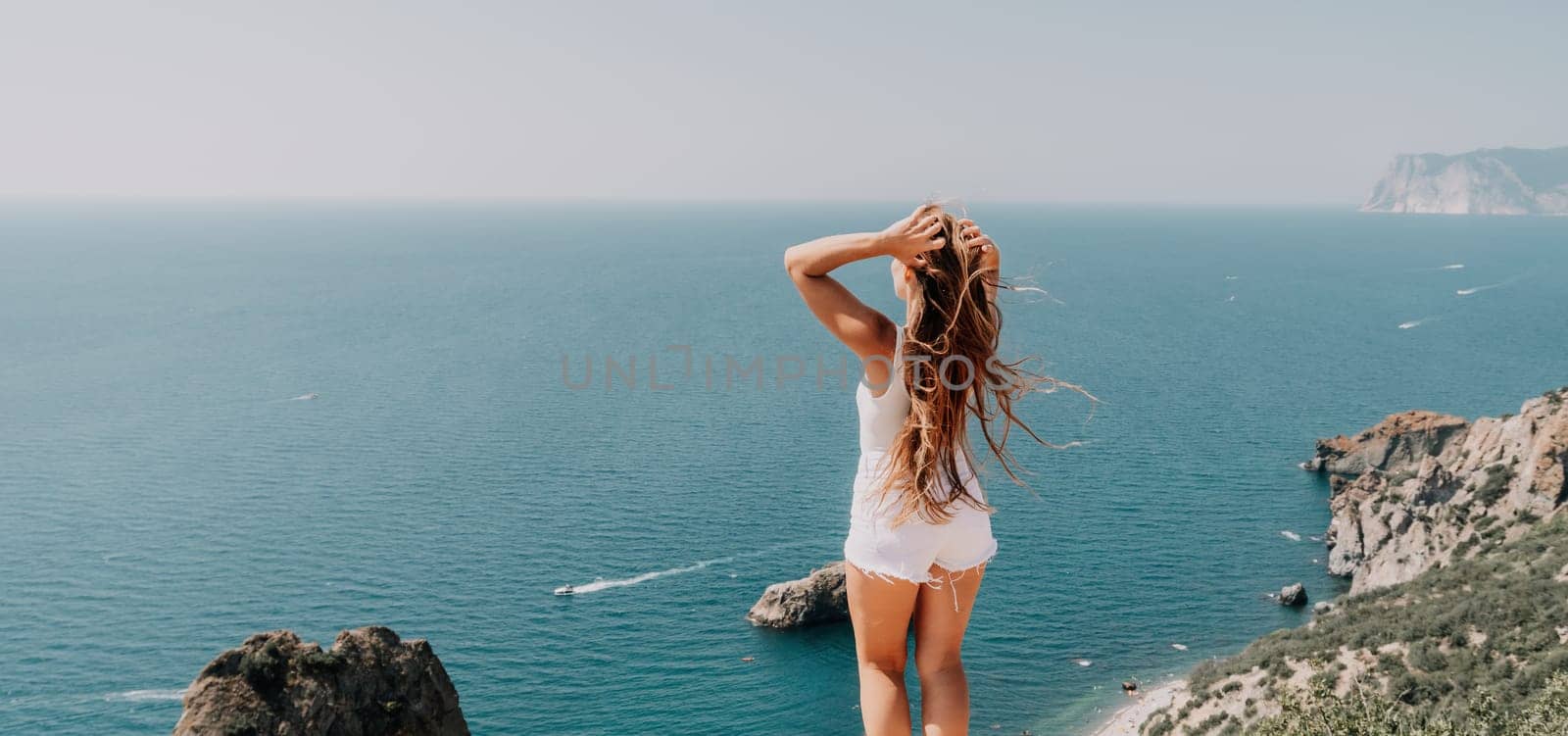 Woman summer travel sea. Happy tourist enjoy taking picture outdoors for memories. Woman traveler posing over sea bay surrounded by volcanic mountains, sharing travel adventure journey by panophotograph