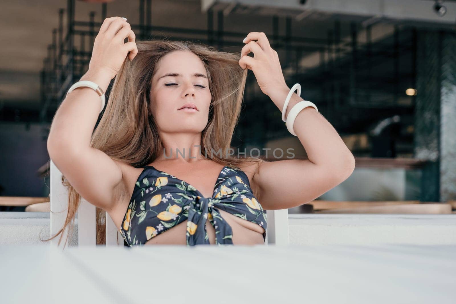 Happy woman portrait in cafe. Boho chic fashion style. Outdoor photo of young happy woman with long hair, sunny weather outdoors sitting in modern cafe