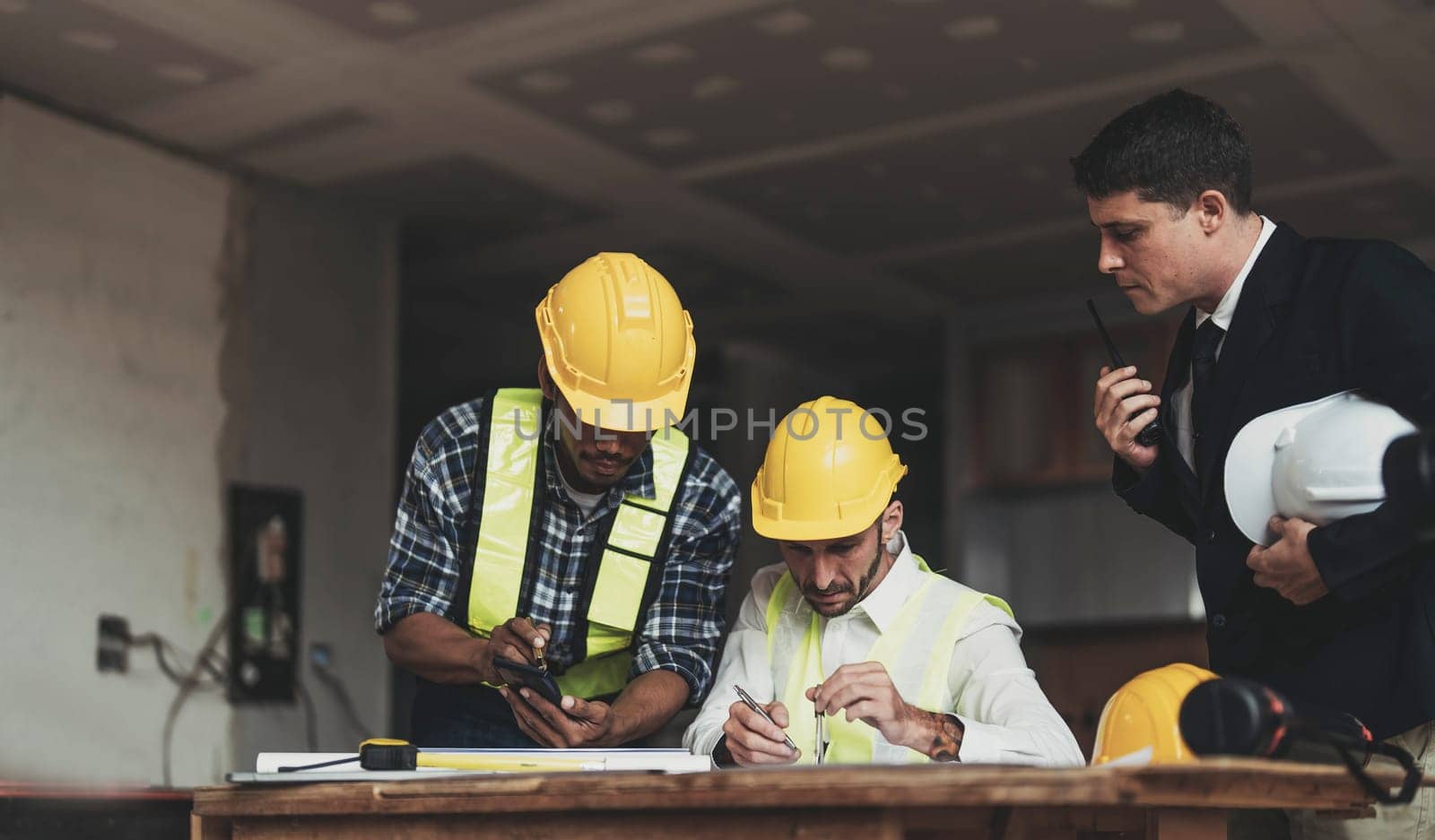 Diverse Team of Specialists Use Laptop on Construction Site. Real Estate Building Project with Engineer Investor and Businessman Checking Area, working on Civil Engineering, Discussing Strategy Plan by wichayada