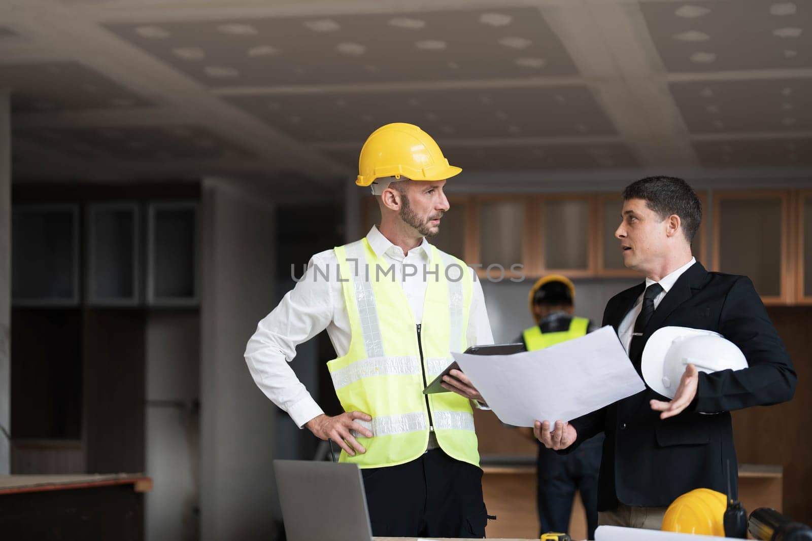 Diverse Team of Specialists Use Laptop on Construction Site. Real Estate Building Project with Engineer Investor and Businessman Checking Area, working on Civil Engineering, Discussing Strategy Plan by wichayada