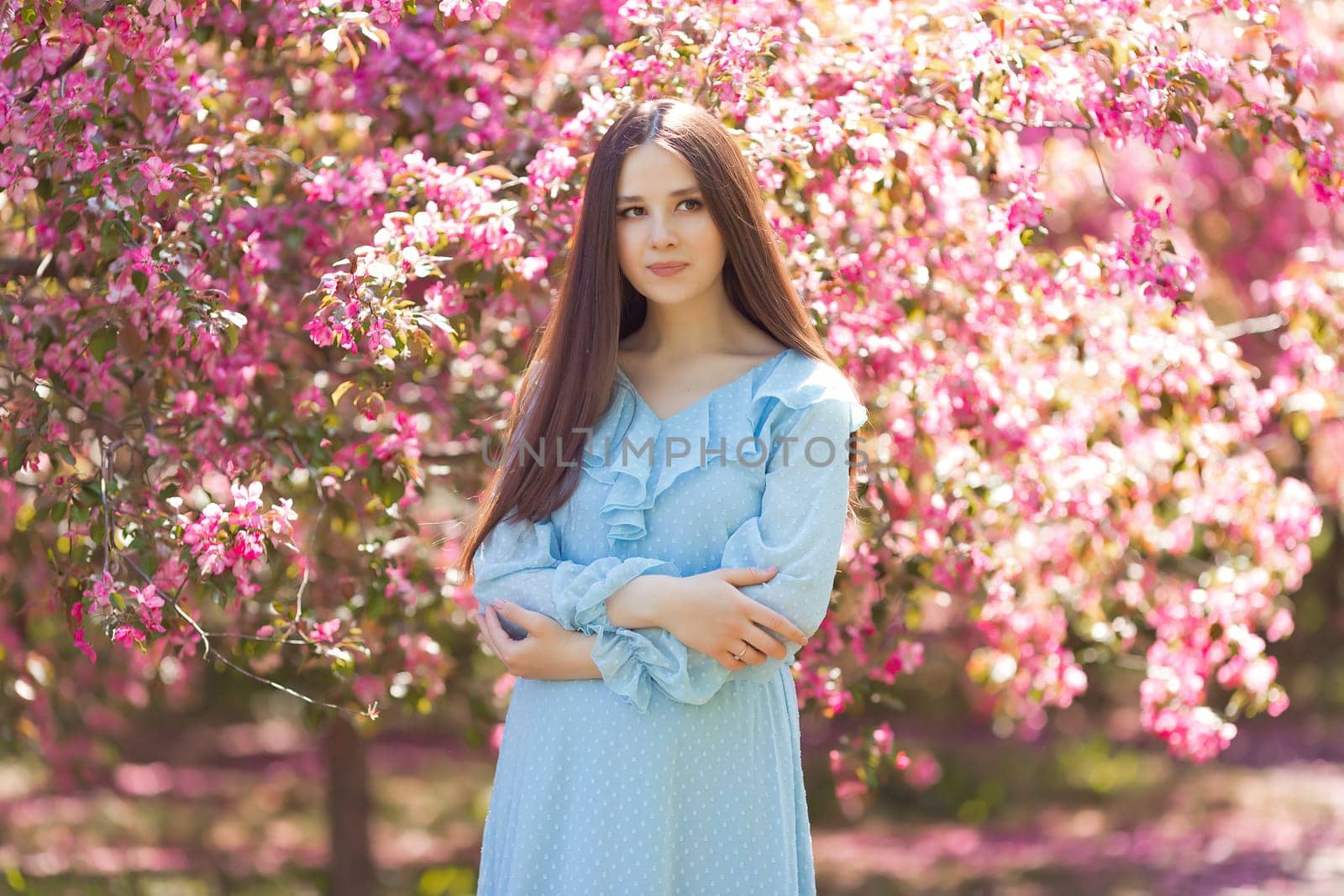 A beautiful girl, standing in a pink blooming garden by Zakharova