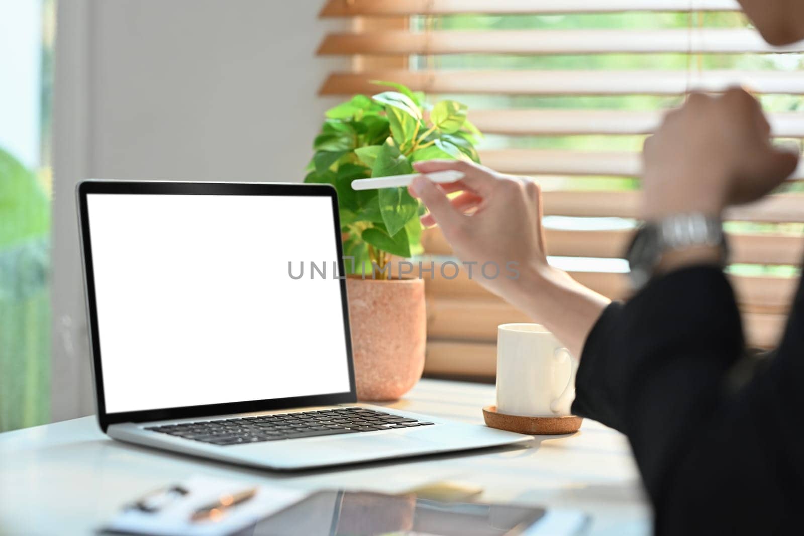 Cropped shot of man worker hand holding stylus pen and pointing on laptop computer screen.