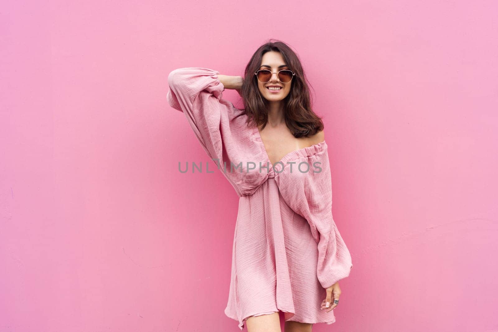 Young beautiful smiling cute romantic woman in trendy summer dress. Carefree woman posing in the street near pink wall. Positive model outdoors in sunglasses. Cheerful and happy.