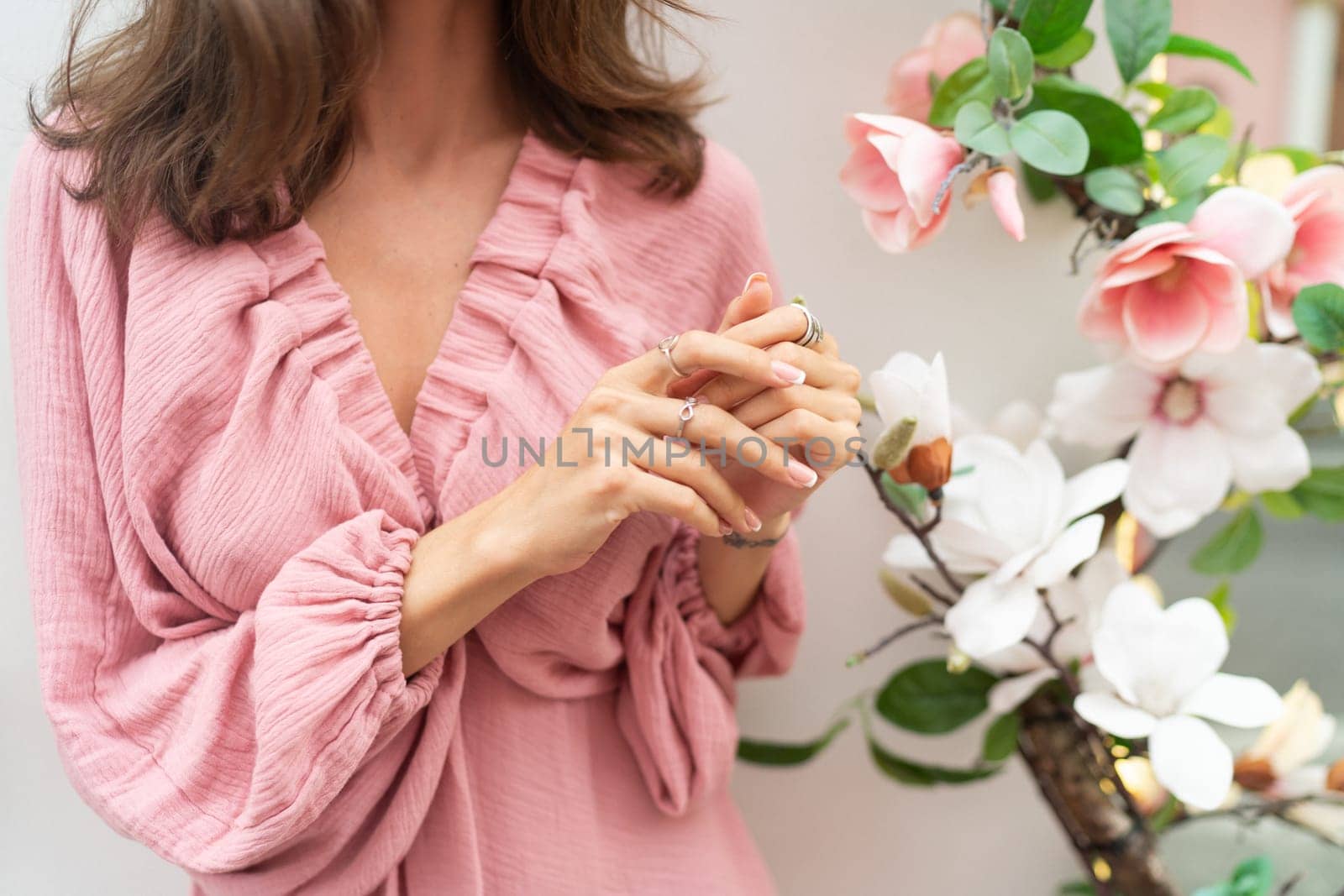 Close shot of romantic cute french gel polish manicure nails. Woman in pink summer dress with flowers around. Rings on fingers. Outdoor shot. by kroshka_nastya