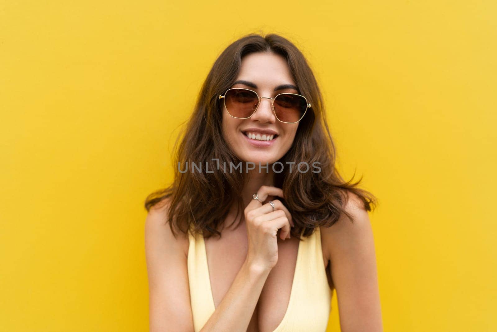 Young beautiful woman. Carefree woman posing in the street near yellow wall. Positive model outdoors in sunglasses. Happy and cheerful