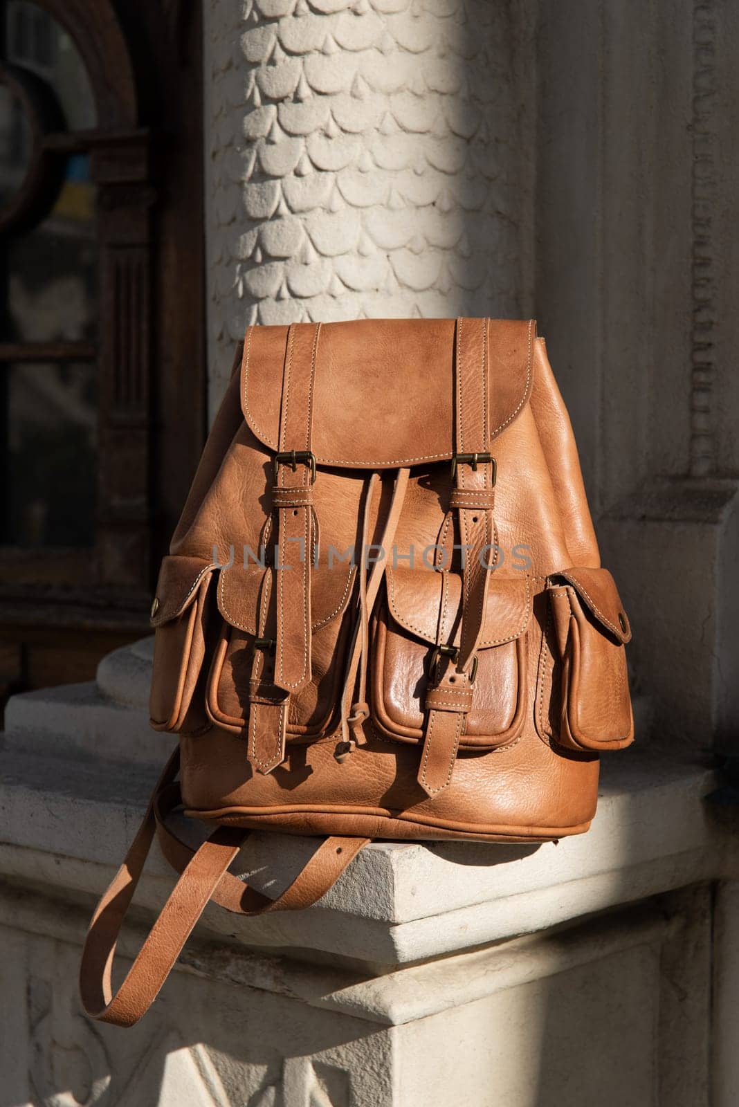 photo of a light brown, retro look leather backpack near column