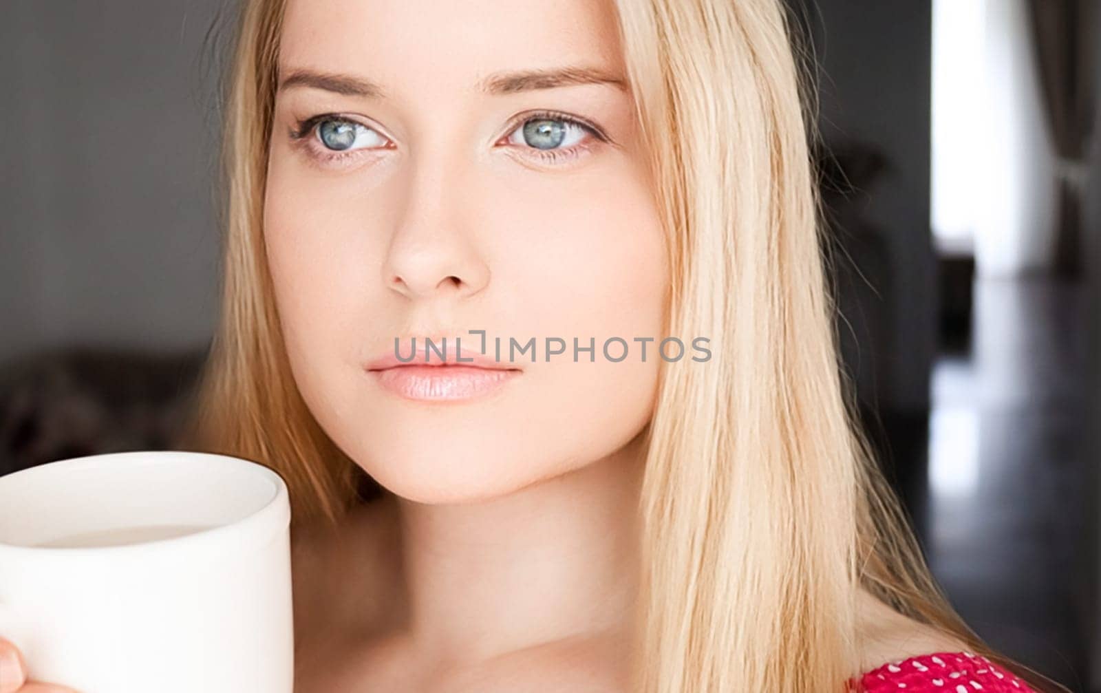 Beautiful blonde woman having a cup of tea in the morning at home by Anneleven