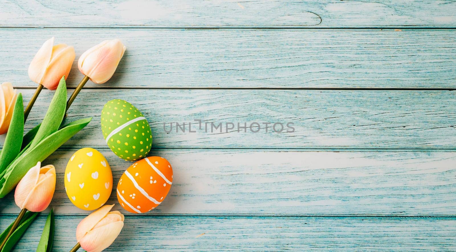 Happy Easter Day Concept. Flat lay holiday banner background web design white colorful easter eggs painted with tulips flowers on blue wood background with empty copy space, overhead, template