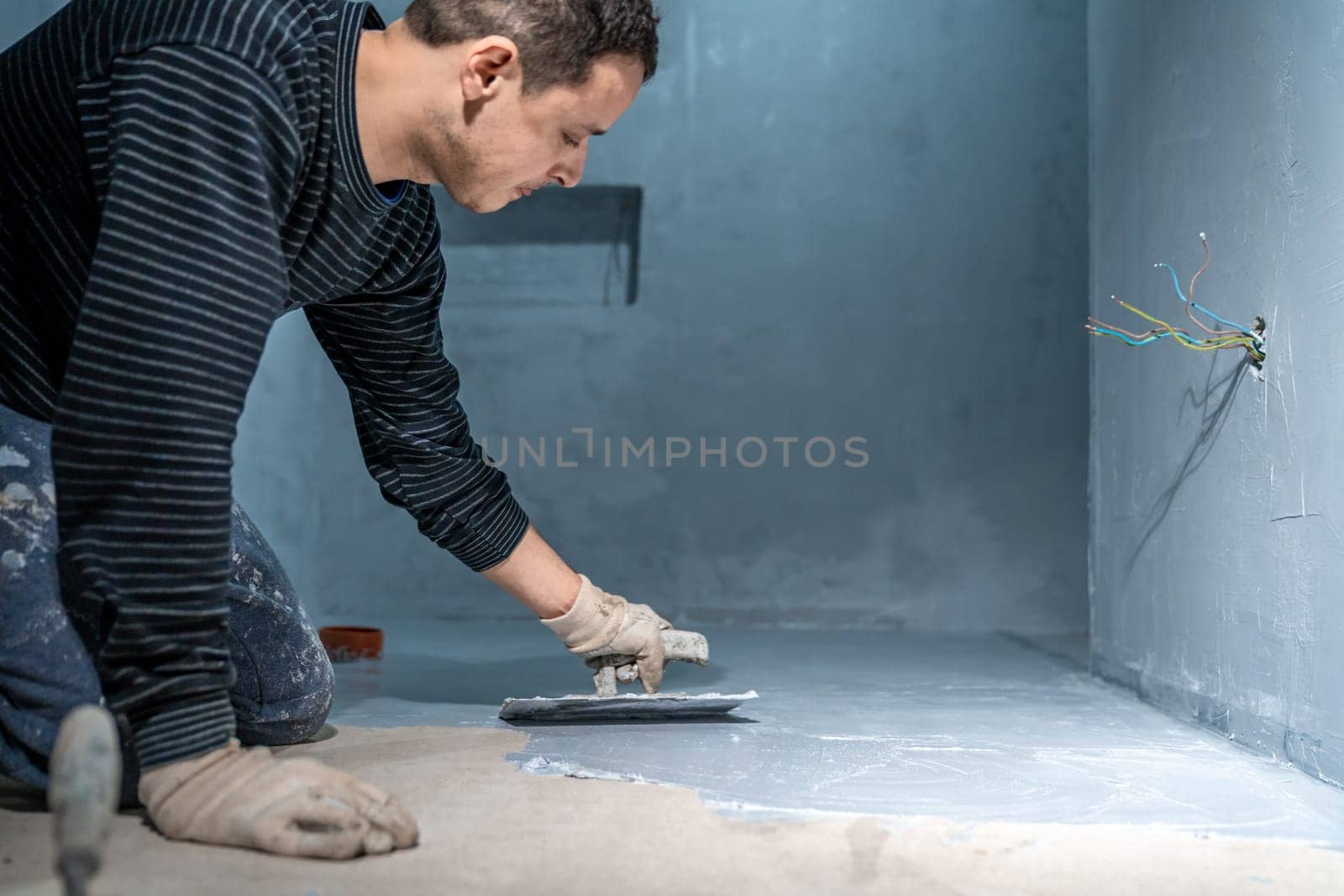 bricklayer works with trowel in room. High quality photo