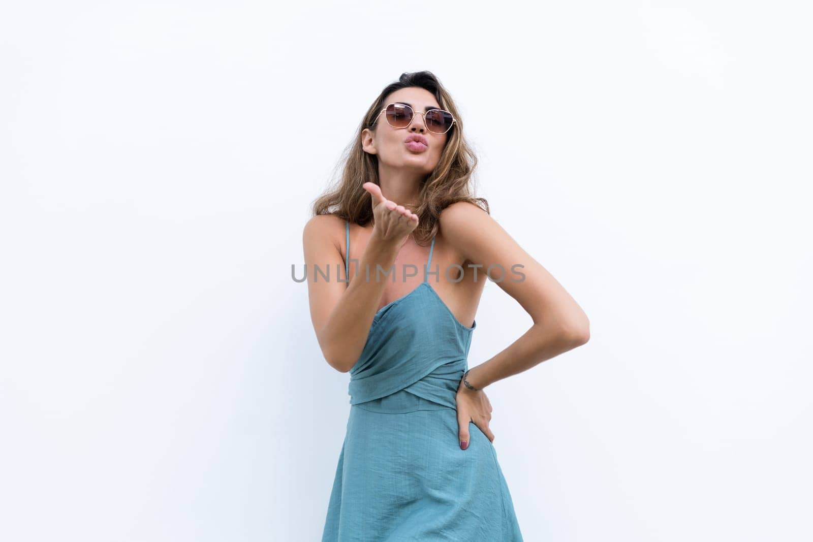 Portrait of beautiful woman in green fitting summer dress on white background natural day light, wearing sunglasses, smiling excited
