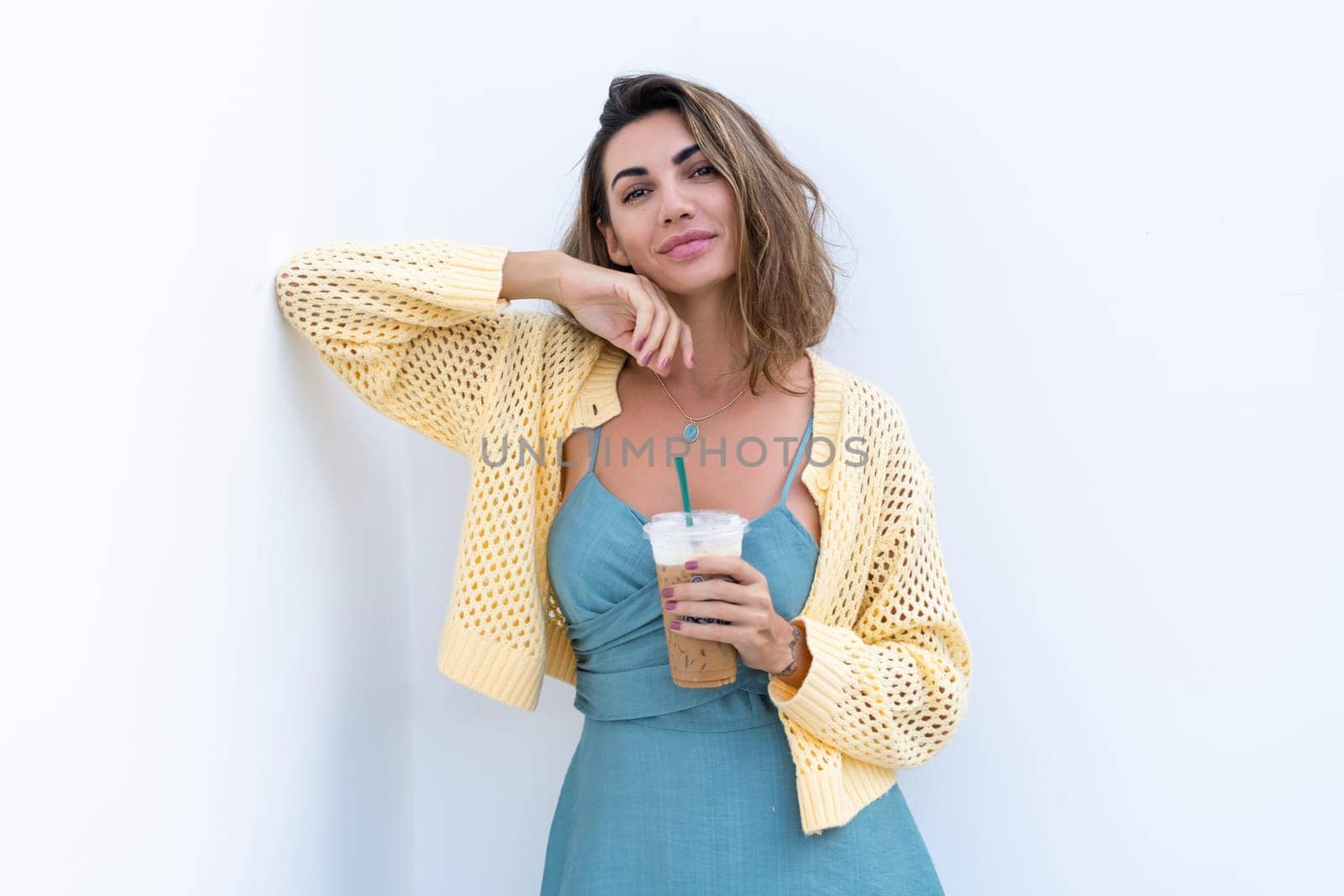 Portrait of beautiful woman in green summer dress on white background natural daylight, holding iced coffee cappuccino happy smiling excited