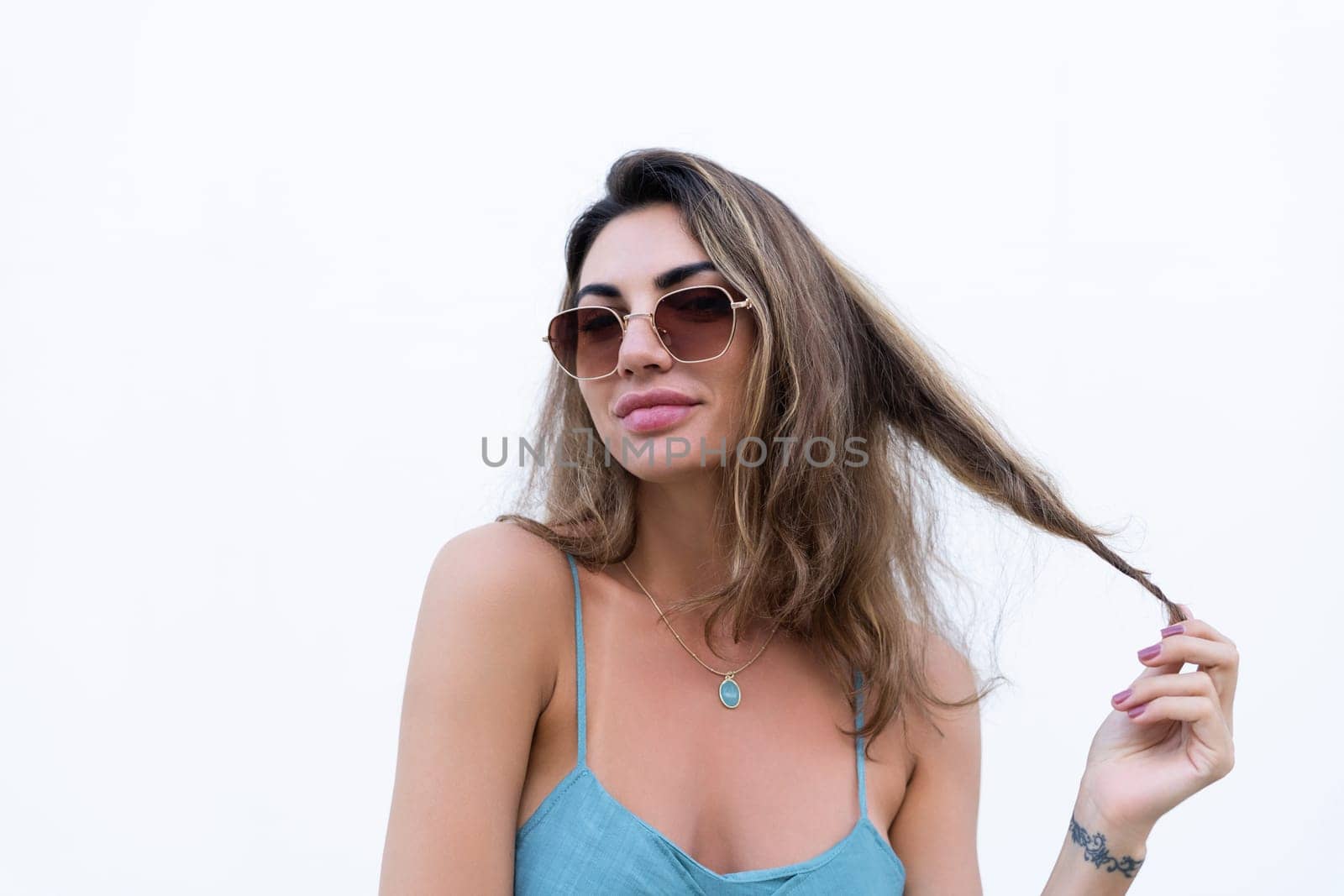 Portrait of beautiful woman in green summer dress on white background natural daylight, wearing sunglasses, smiling excited