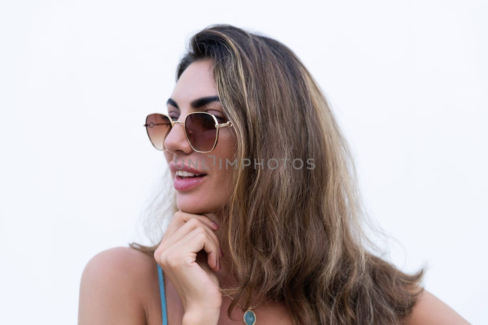 Portrait of beautiful woman in green summer dress on white background natural daylight, wearing sunglasses, smiling excited