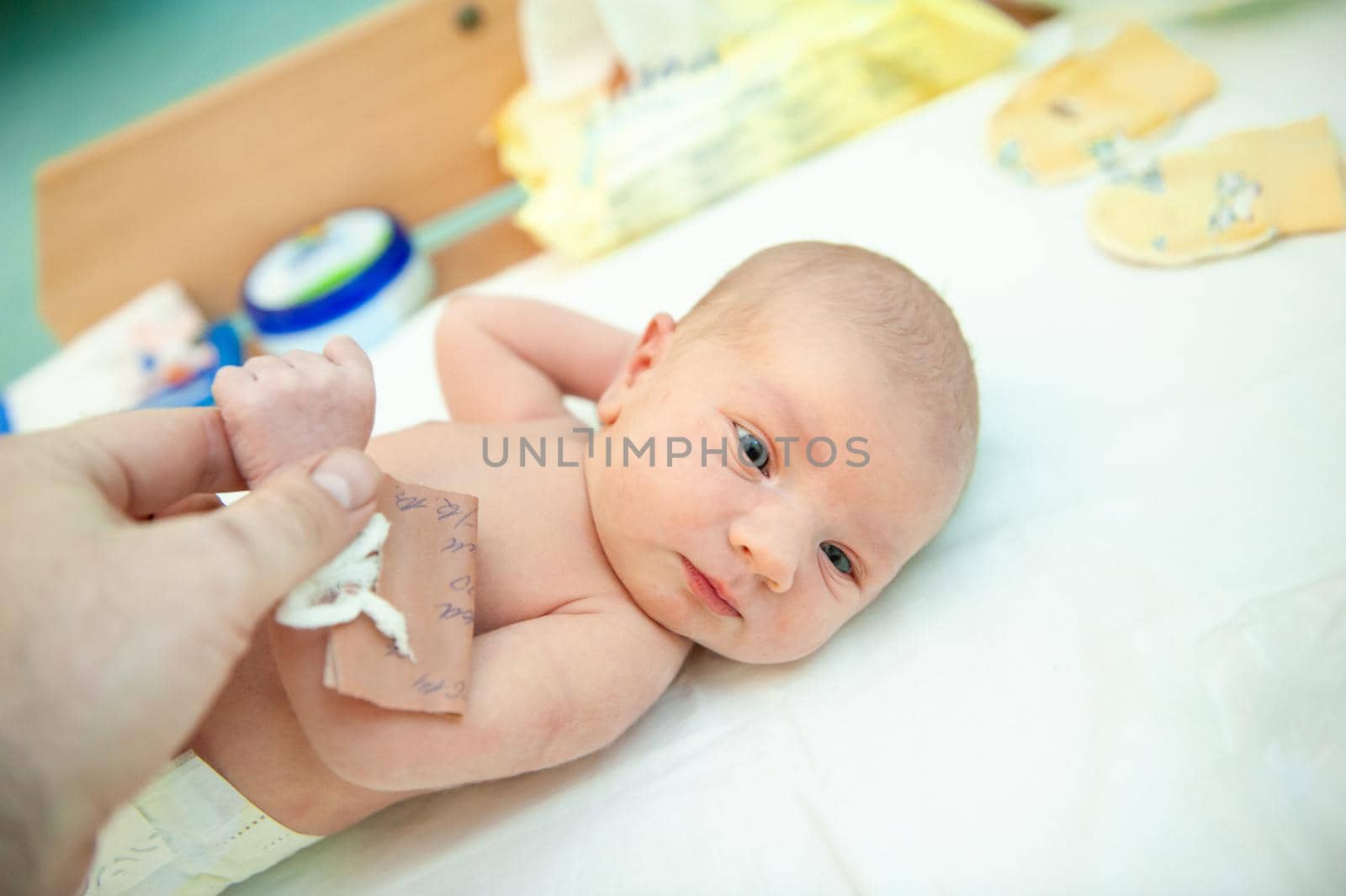 a newborn child on the first day of his birth in the maternity hospital holds his father's finger by Lobachad