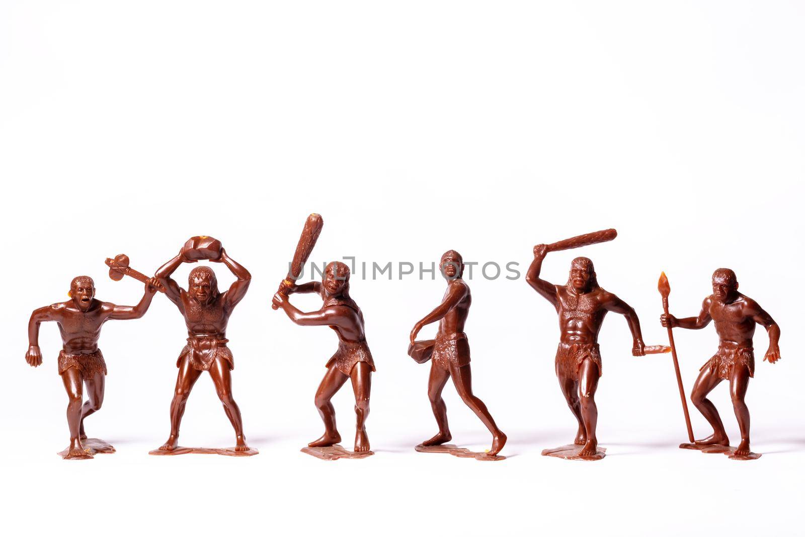 Large toy figures of primitive people on a white background.