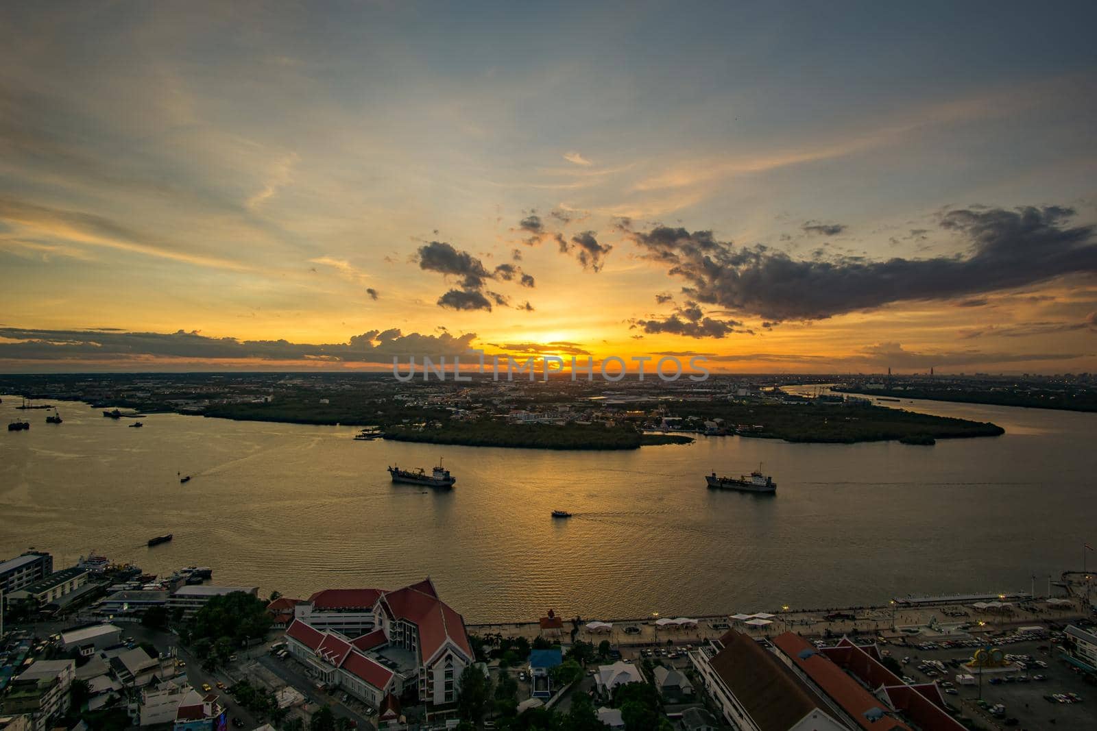 Bird's eye view of Samut Prakan, Thailand. Sunset over the Chao Phraya River, orange sky.