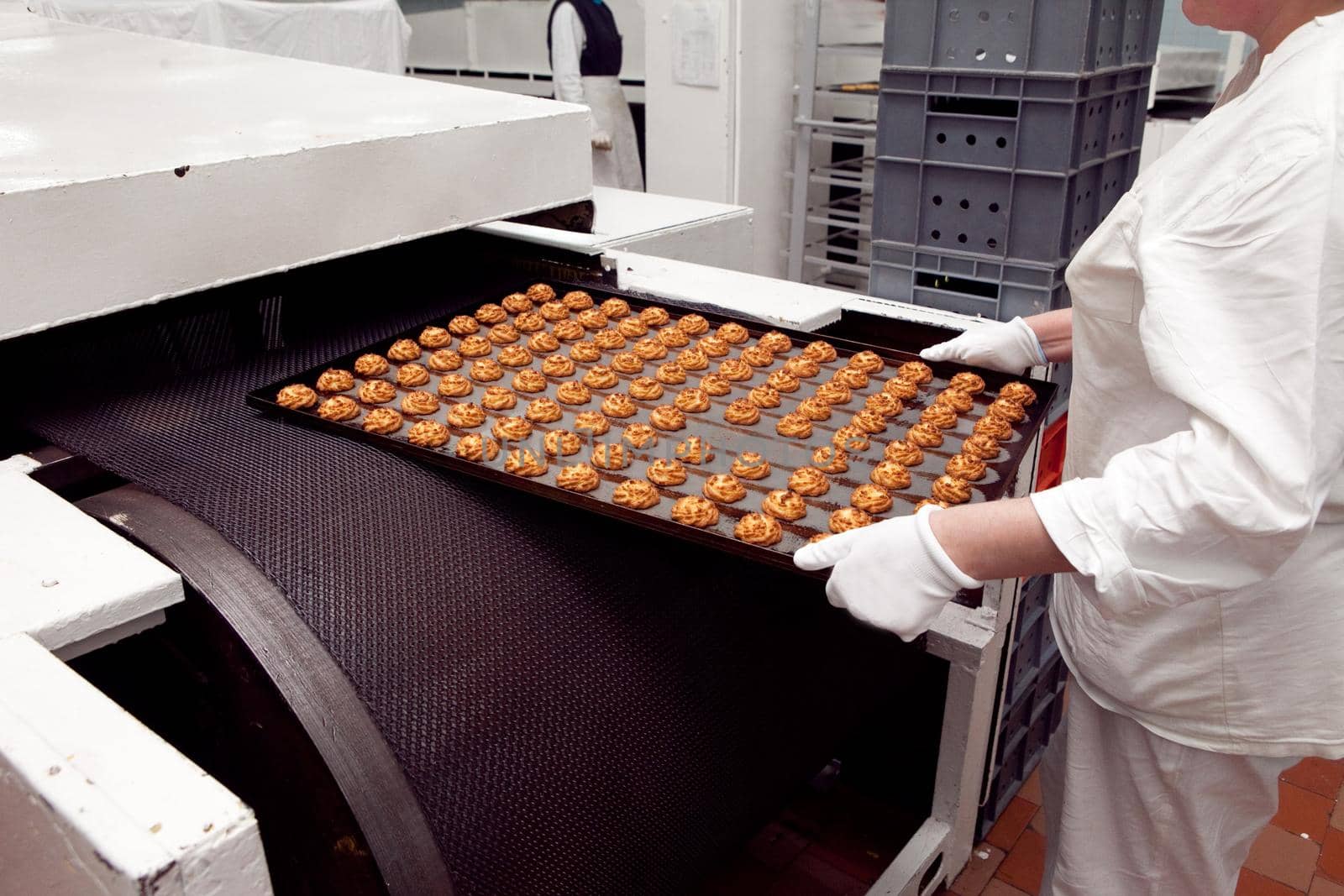 A tray of ready-made cookies is taken from the conveyor belt in the bakery.