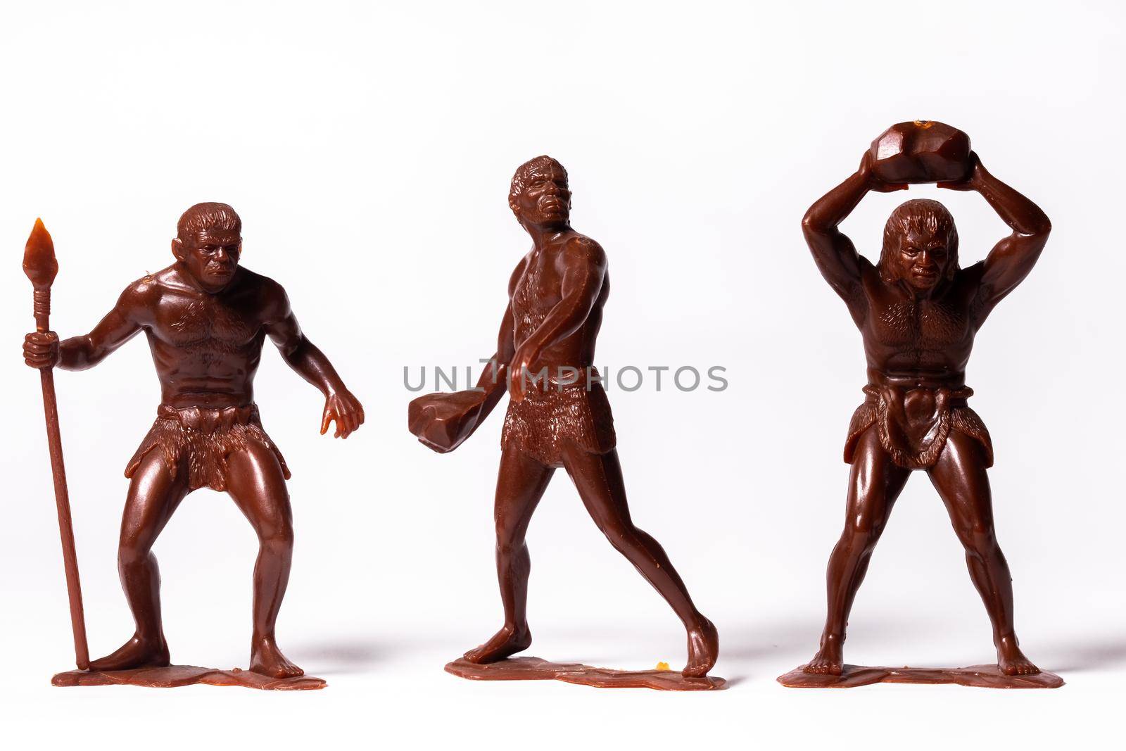 Large toy figures of primitive people on a white background.