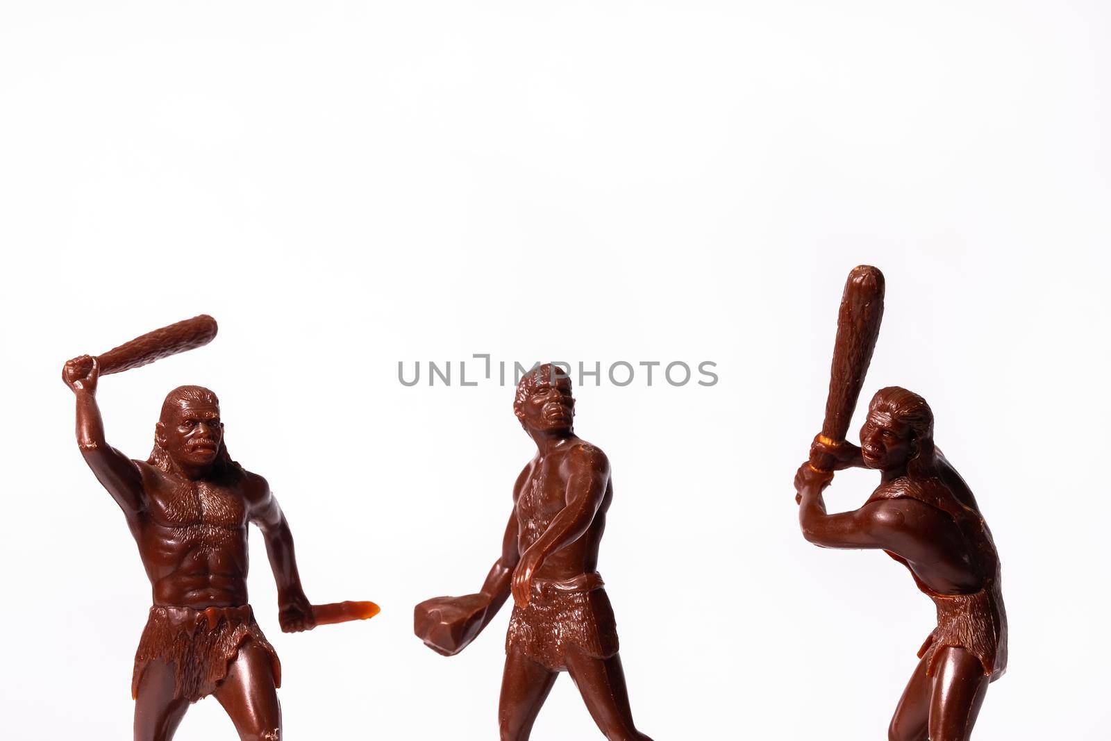 Large toy figures of primitive people on a white background.