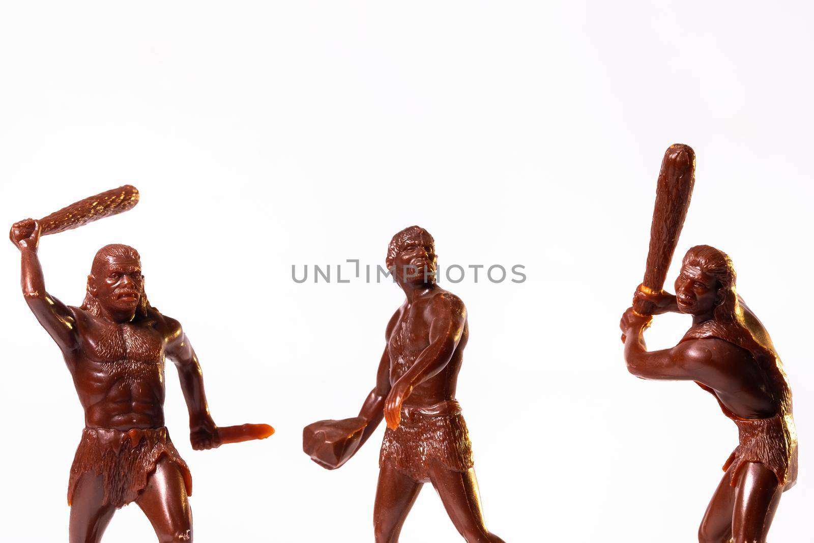 Large toy figures of primitive people on a white background.