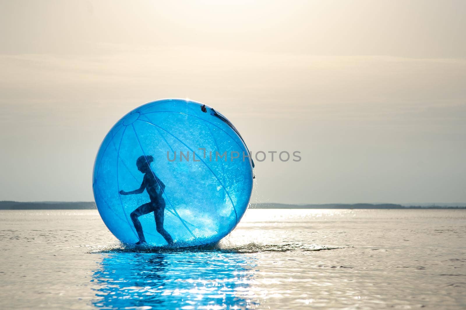 A girl in an inflatable attraction in the form of a ball on the sea.