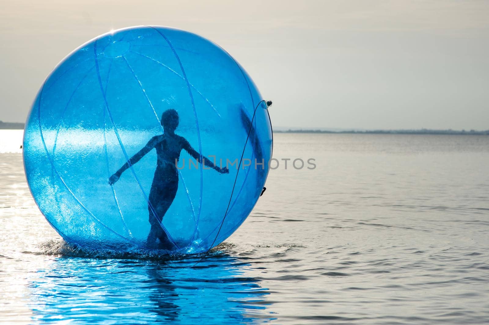 A girl in an inflatable attraction in the form of a ball on the sea.