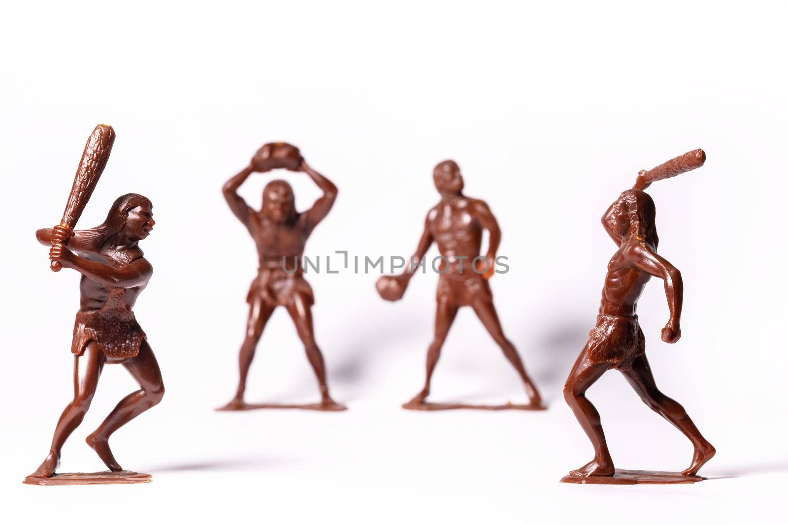 Large toy figures of primitive people on a white background.