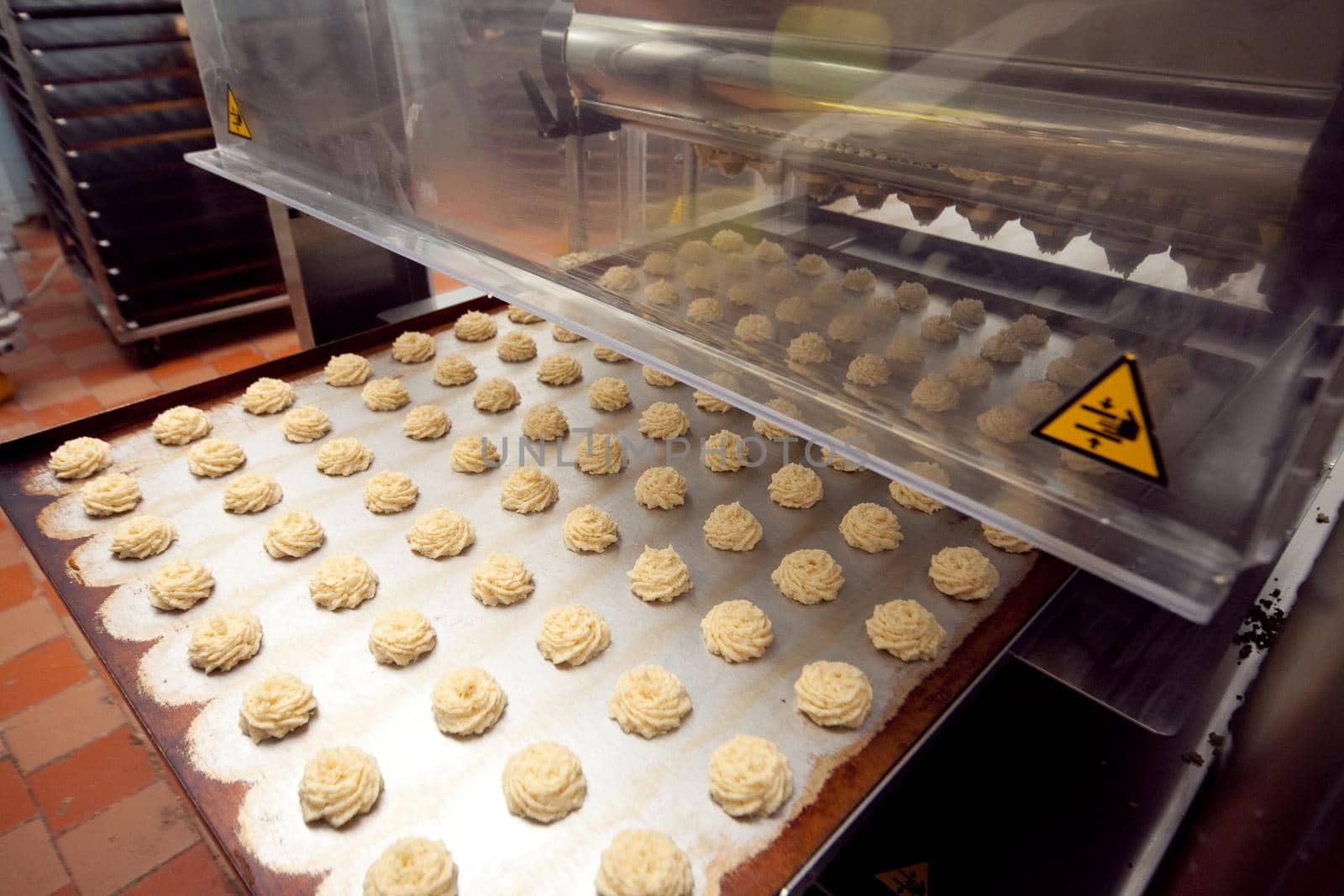 A tray of ready-made cookies is taken from the conveyor belt in the bakery.