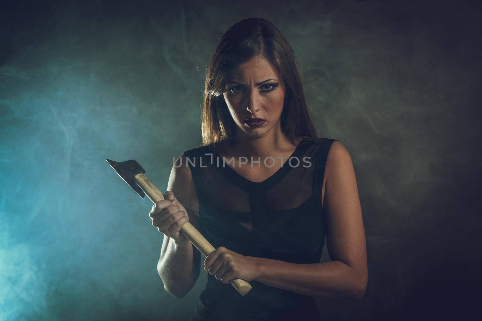 Beautiful dangerous girl with rusty axe want to revenge for violence she experience. Looking at camera.
