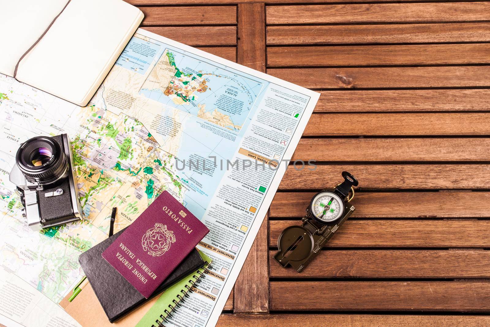 Top view of compass, photocamera, block notes, passport and map on a wooden table