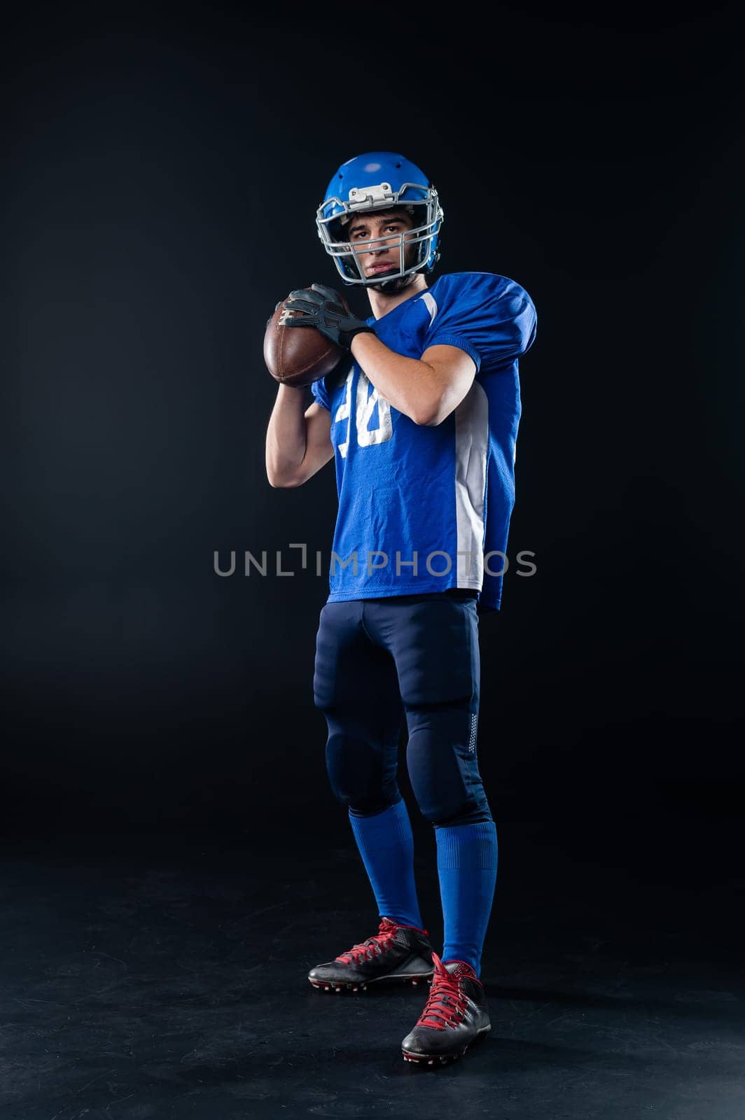 Portrait of a man in a blue uniform for american football on a black background