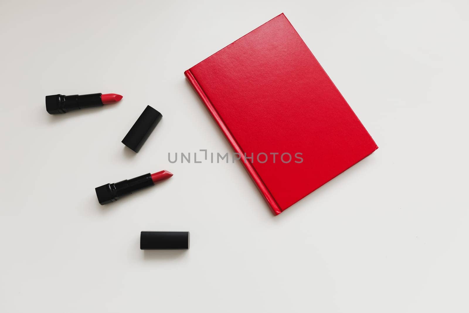 Concept Women's Day, Valentines Day, March 8. Red book and lipsticks, cosmetic makeup products and accessories flatlay top view by paralisart