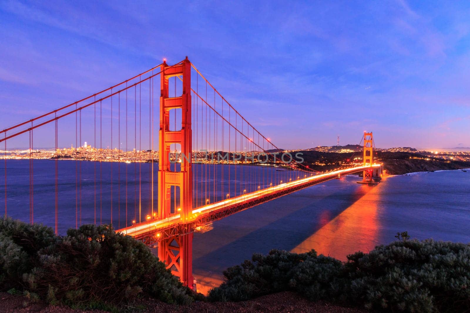 Car lights blur over Golden Gate Bridge and San Francisco lit at night by Osaze