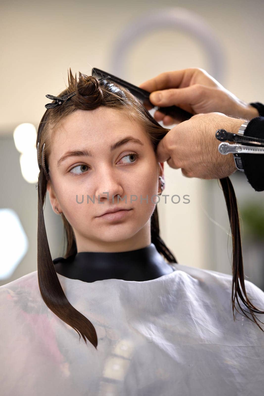 male hairdresser is combing the hair of the female client. by erstudio