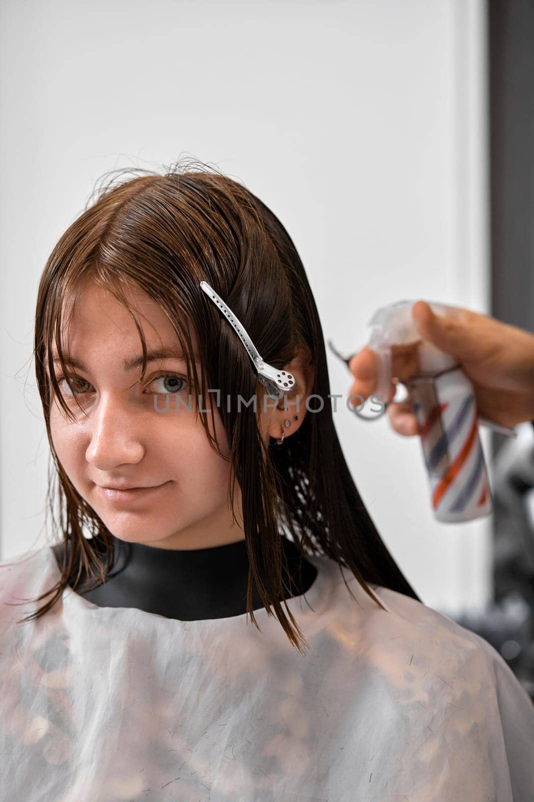 Professional male hairdresser cutting female hair in salon