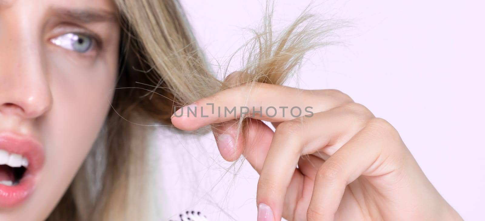 Closeup alluring portrait of beauty cosmetic clean skin woman having brittle dry hair problem. Grimacing frustrated sad facial expression in pink isolated background. Damaged and hair loss concept.